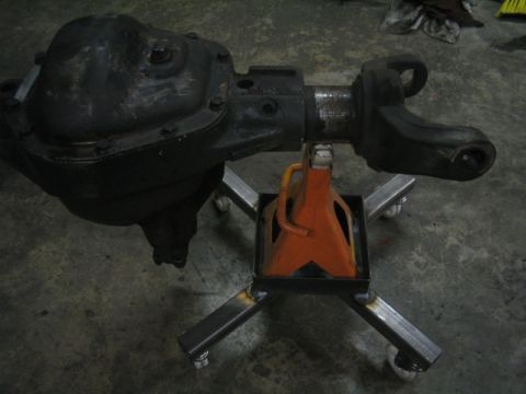 1979 Ford Bronco - A vehicle axle assembly is supported by a custom metal stand with an orange jack.