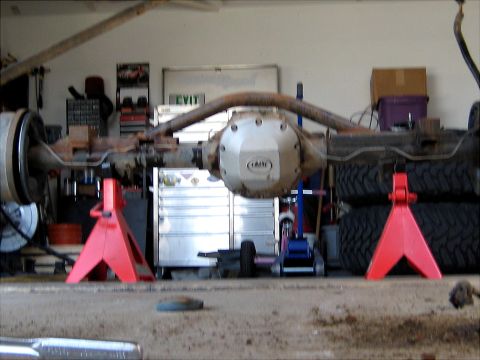 1996 Ford Bronco - Rear axle assembly, likely from a Ford Bronco, is supported by red jack stands in a garage setting.