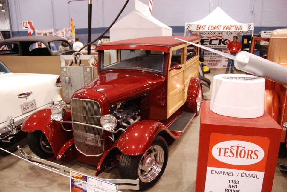 red woody wagon hot rod with exposed engine, next to a white car and a tent in the background