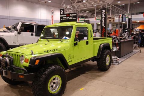 1996 Ford Bronco - A lime green Jeep Brute pickup truck is displayed indoors next to a white Jeep Wrangler.