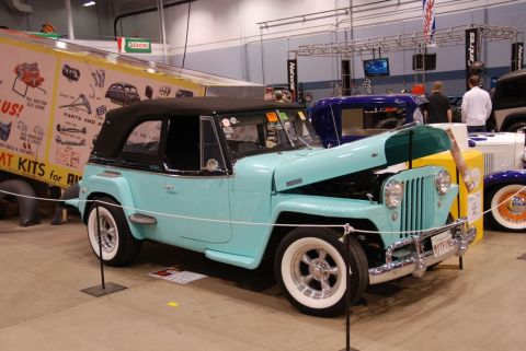 1996 Ford Bronco - A vintage Jeep Willys CJ-3A is displayed indoors with its hood up, next to other vehicles and a trailer.