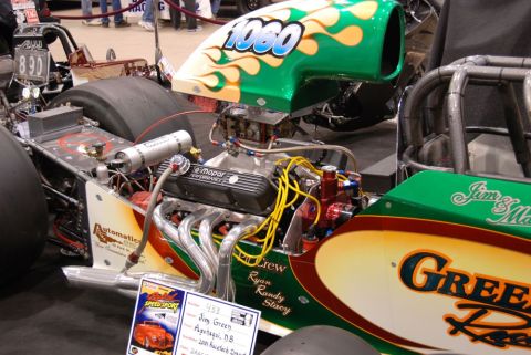 1996 Ford Bronco - A drag racing car with a prominent engine and custom paintwork is displayed indoors.
