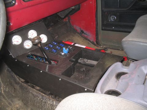 1979 Ford Bronco - Custom fabricated black sheet-metal center console in a truck cab, fitted with four white-face Auto Meter gauges, a bank of blue-lit rocker…