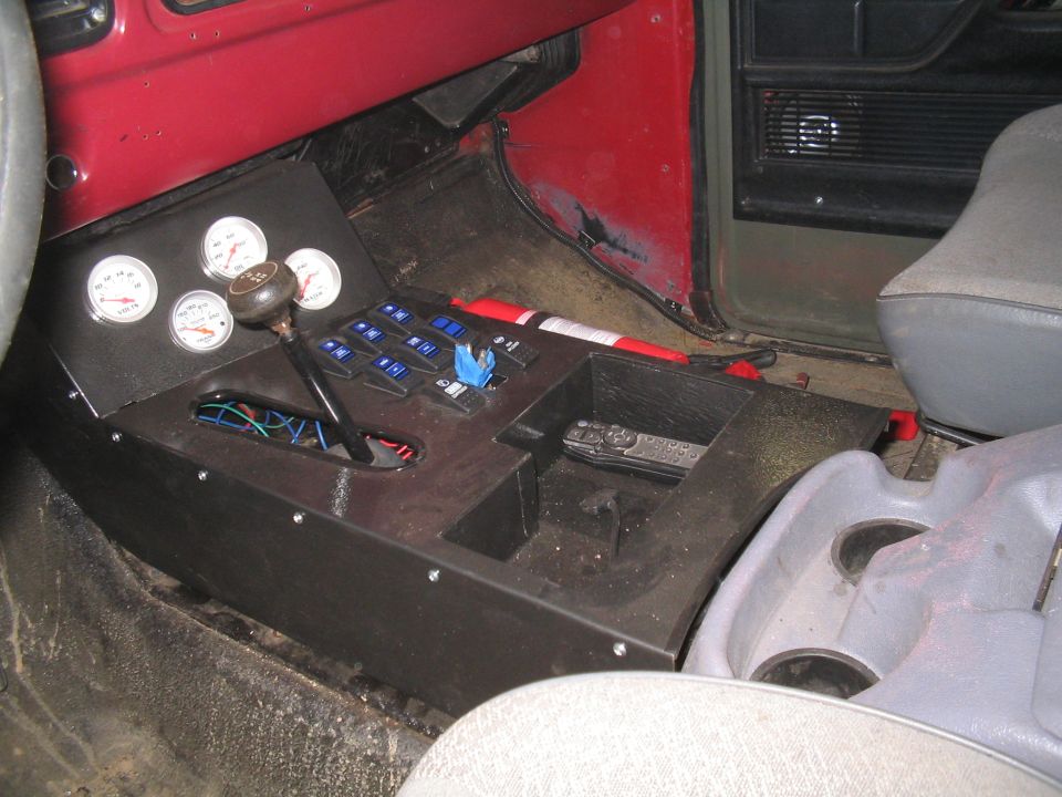 Custom black metal center console with white gauges, blue rocker switches and shifter