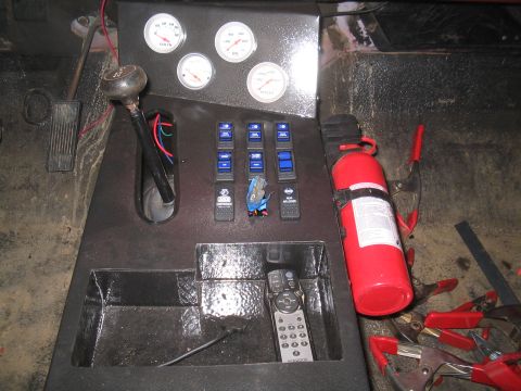 1979 Ford Bronco - Overhead shot of a shop-built center console finished in bedliner-style black coating, with a four-gauge panel (volts, oil pressure, water…