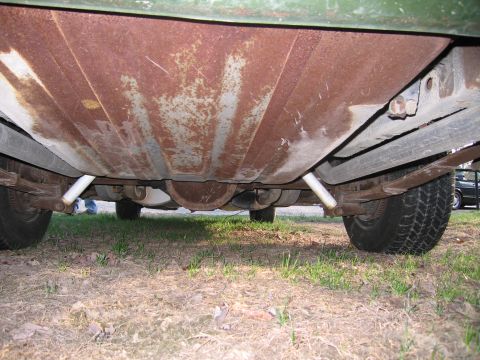 1991 Ford LTD Crown Victoria - The underside of a green vehicle reveals significant rust on the fuel tank and suspension components.