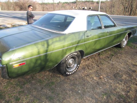 1991 Ford LTD Crown Victoria - A green sedan with a white roof is parked outdoors on a grassy area next to a road.