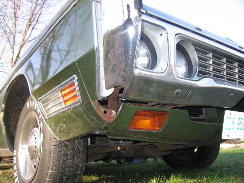 1991 Ford LTD Crown Victoria - Front view of a vintage green car, focusing on the bumper and headlight assembly.