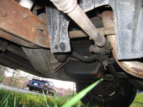 1991 Ford LTD Crown Victoria - View of underbody components with a blue convertible driving in the background.