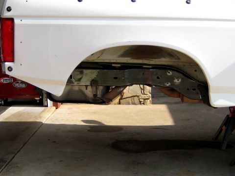 1996 Ford Bronco - The rear suspension and frame of a white vehicle are visible, with a red toolbox in the background.
