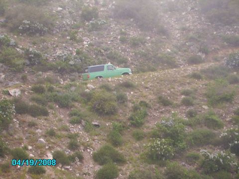 1990 Ford Bronco - A green 1990 Ford Bronco is seen driving on a dirt road on a hillside.