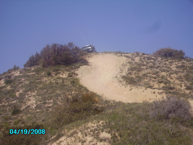 SUV climbing a sandy hill with a dirt track