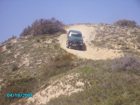 1990 Ford Bronco - 1990 Ford Bronco navigating an off-road trail on a sunny day.