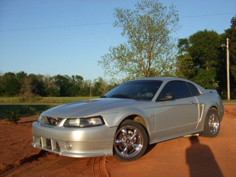 1999 Ford Mustang - A silver 1999 Ford Mustang coupe is shown from a 3/4 front angle on a dirt road.