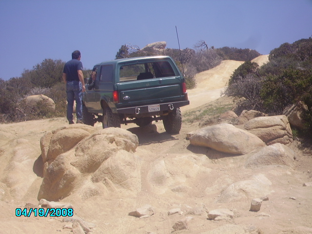Green 1990 Ford Bronco on a rocky off-road trail