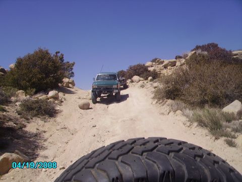 1990 Ford Bronco - A green 1990 Ford Bronco navigates a dusty, rocky trail with another vehicle behind it.