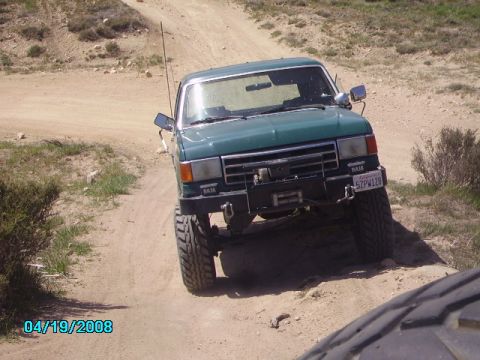 1990 Ford Bronco - This modified Ford truck is navigating a rough, off-road trail.