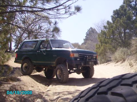 1990 Ford Bronco - This lifted 1990 Ford Bronco navigates a dusty trail, its off-road capabilities.