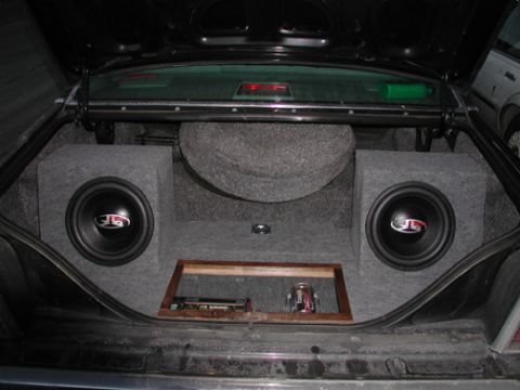 1988 Ford LTD Crown Victoria - Custom car-audio installation in a sedan's trunk: the entire compartment is finished in gray carpet with two subwoofers mounted in separate…