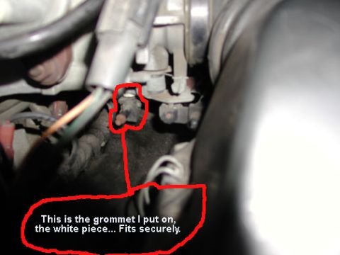 1988 Ford LTD Crown Victoria - Annotated close-up inside a dark engine bay with a red hand-drawn circle around a small rubber grommet on a bracket, connected to a caption…