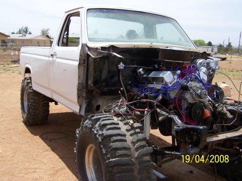 1995 Ford Bronco - White Ford pickup truck with engine exposed and large off-road tires, photographed in 2008.