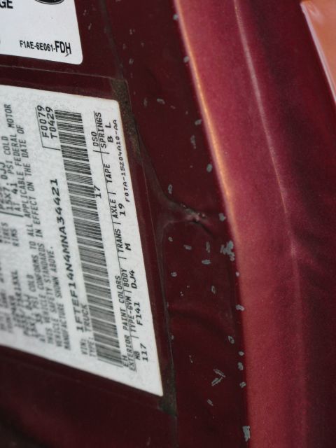 1991 Ford F-150 - Door jamb sticker detail on a red vehicle, with visible paint chips on the body panel.