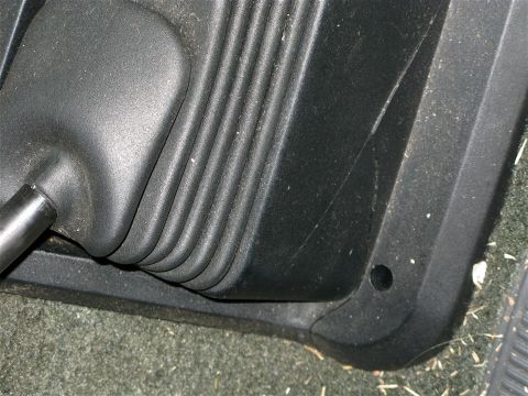 1991 Ford F-150 - Close-up of a vehicle's gear shifter boot and surrounding interior trim, with visible dust and debris.