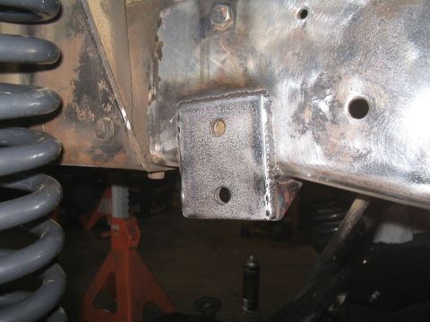 1979 Ford Bronco - Close-up of a custom welded bracket attached to a vehicle's frame, with suspension components in view.