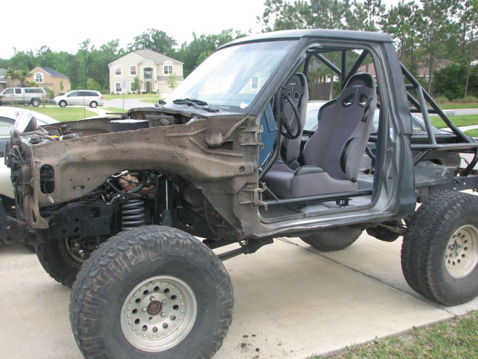 Side view of a stripped pickup chassis build with roll cage and race seat