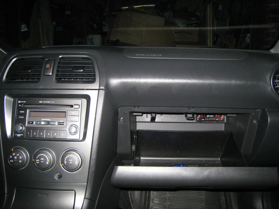 2007 Subaru Impreza interior dashboard with radio and open glove box showing an aftermarket device