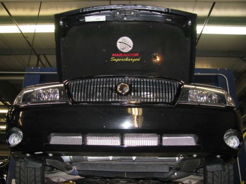 2003 Mercury Marauder - The hood of a black 2003 Mercury Marauder is open, revealing the 'Marauder Supercharged' emblem and the front grille.