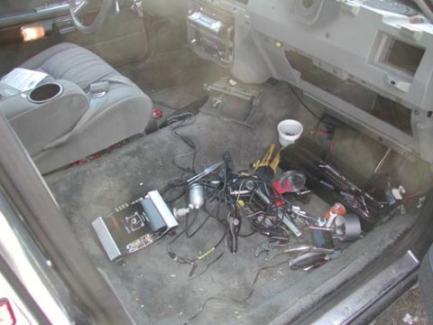 1988 Ford LTD Crown Victoria - Overhead view into a car interior mid-install through the open door: the dash is stripped to bare metal with panels removed, and the gray c…