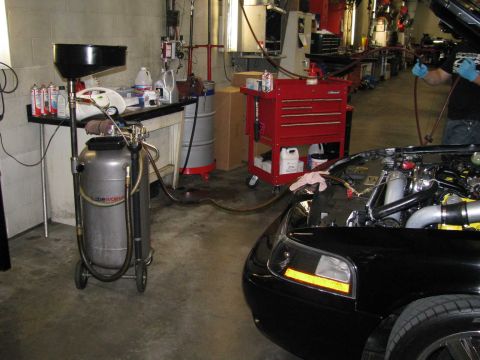 2003 Mercury Marauder - A black car's front fender and engine bay are visible next to automotive service equipment in a garage.