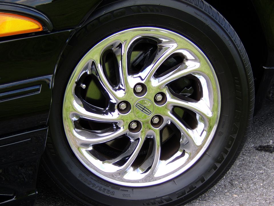 Chrome Lincoln alloy wheel with Uniroyal P225/60R16 tire on a black car