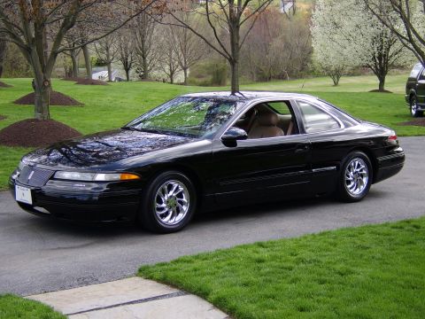 1996 Mercury Grand Marquis - A black Lincoln Mark VIII coupe is parked on a driveway in front of a grassy lawn and trees.