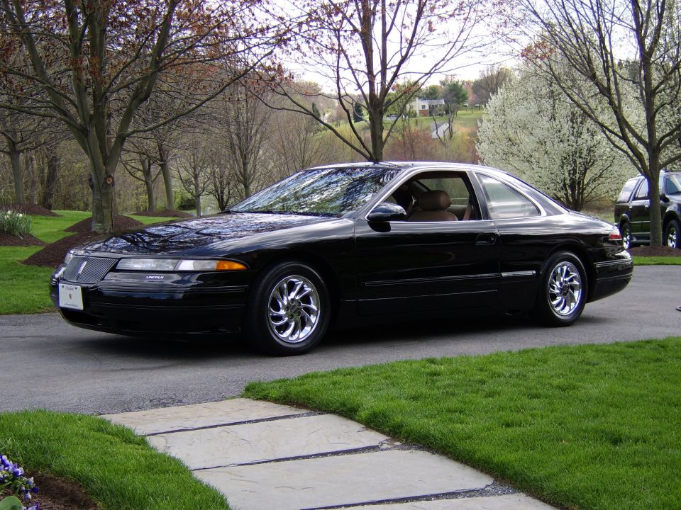 Black Lincoln Mark VIII coupe on a driveway, front 3/4 view with chrome wheels