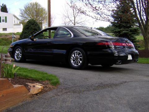 1996 Mercury Grand Marquis - A black coupe is parked on a residential driveway, viewed from the rear three-quarter angle.