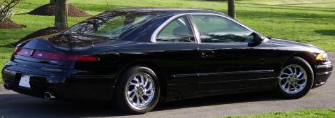 1996 Mercury Grand Marquis - A black coupe is parked on a paved driveway with grass and trees in the background.
