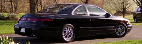 1996 Mercury Grand Marquis - A black coupe is parked on a driveway with trees and grass in the background. Another vehicle is parked to the right.