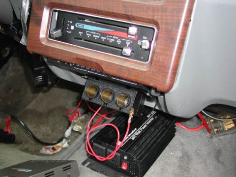 1988 Ford LTD Crown Victoria - Under-dash view of a woodgrain center stack with slide-lever heater controls above a three-hole gauge or switch pod, and a black 360-watt p…