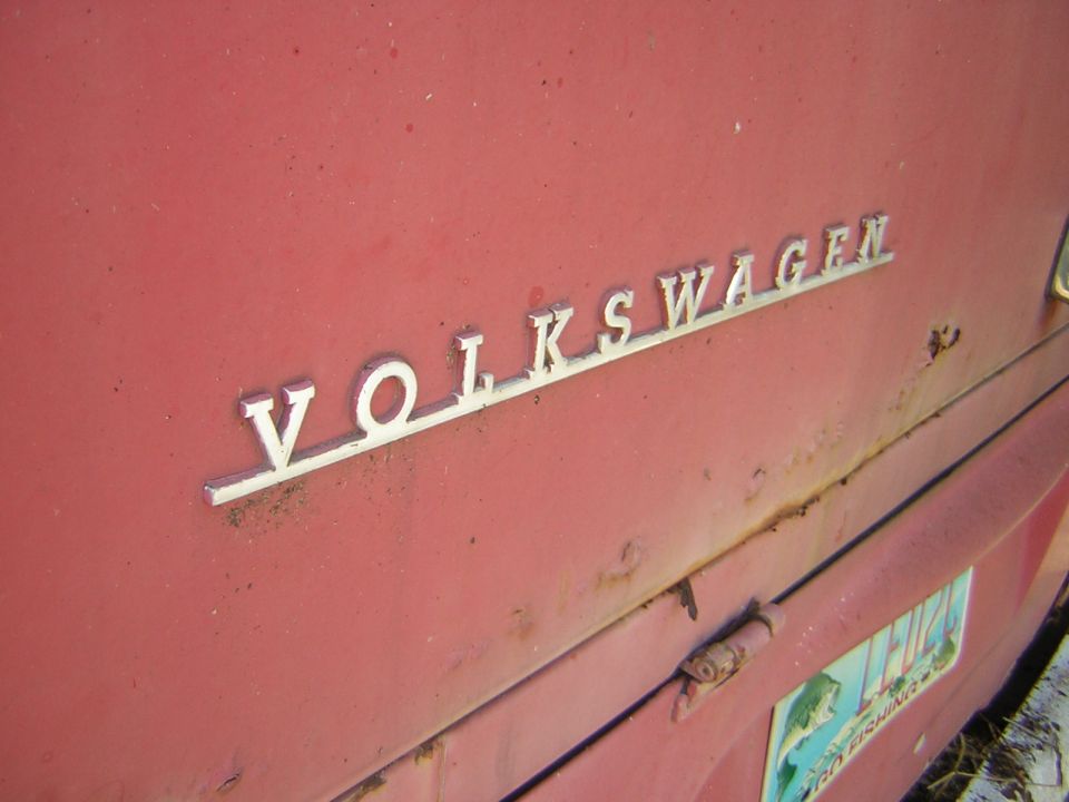 Close-up of VOLKSWAGEN lettering on a red vehicle. License plate visible