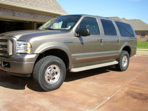 1995 Ford Bronco - This Ford Excursion SUV is parked in front of a garage and house on a sunny day.