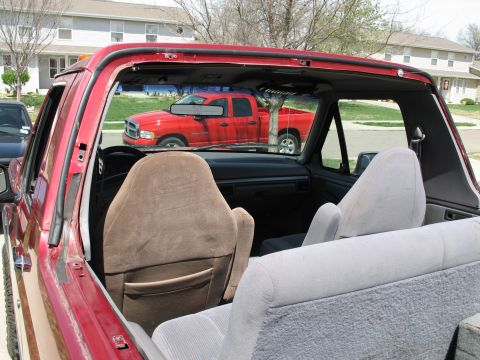 1995 Ford Bronco - Interior view of a red SUV, looking through the windshield at a red pickup truck parked outside.