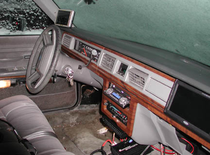 1988 Ford LTD Crown Victoria - Passenger-side view of a gray Ford sedan dashboard with woodgrain trim, four-spoke steering wheel and keys in the ignition, fitted with an…