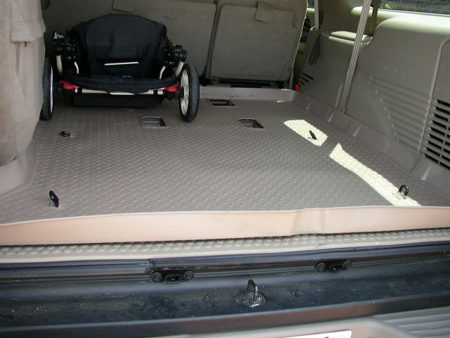 Interior cargo area of an SUV with a folded stroller and tie-down hooks