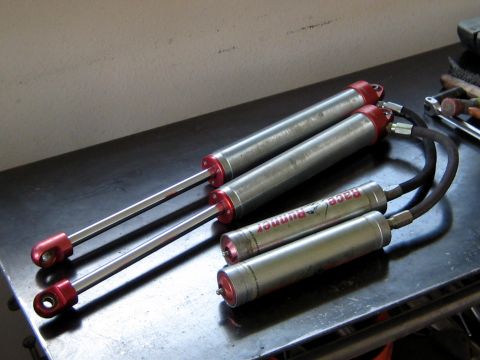 1996 Ford Bronco - Two pairs of shock absorbers, one set labeled 'Race Runner', are displayed on a dark surface.