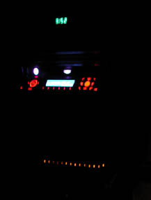 1988 Ford LTD Crown Victoria - Night interior shot of a car's center stack with the lights off, showing an illuminated aftermarket head unit with a blue-lit display and r…