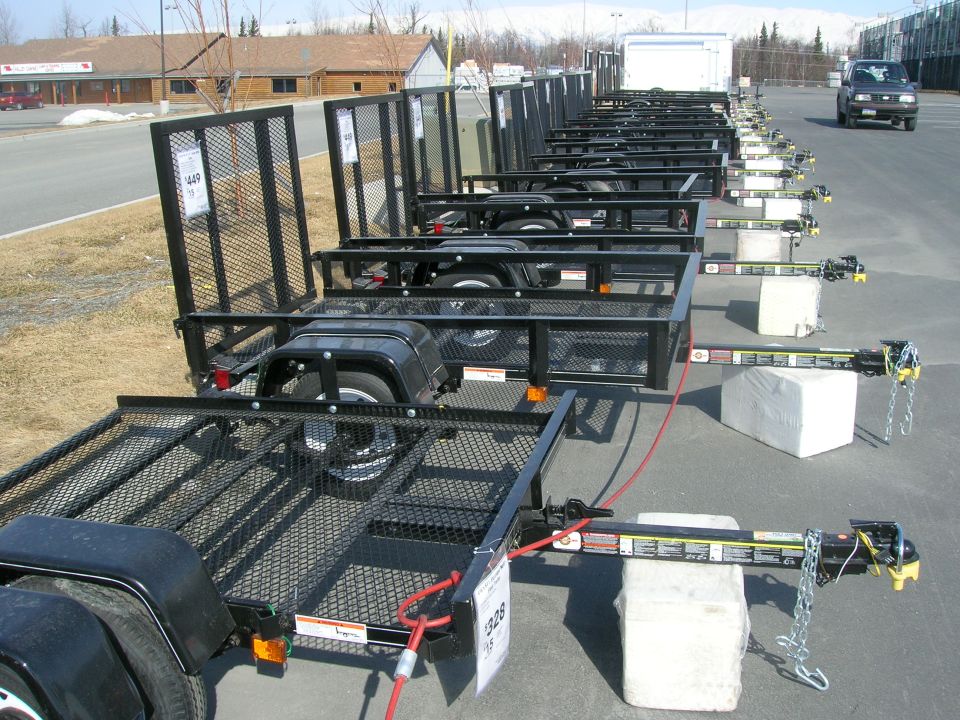 Row of black utility trailers parked on pavement