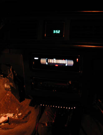 1988 Ford LTD Crown Victoria - Night view of a car's center stack showing a green digital clock reading 3:52 set into the dash above an illuminated Sony head unit with a…