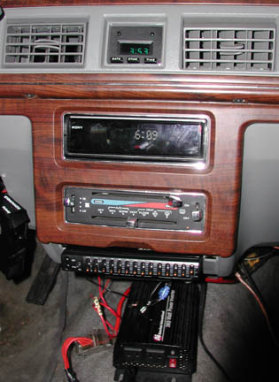 1988 Ford LTD Crown Victoria - Interior shot of a woodgrain center stack with a green digital date/time display in the upper dash between two rectangular vents, a Sony he…
